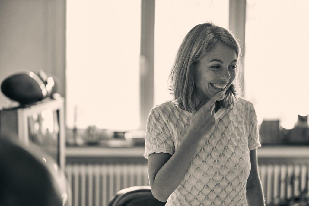 Woman in white textured top smiling in modern kitchen with warm natural lighting - © Pascal Recchia. All rights reserved.
