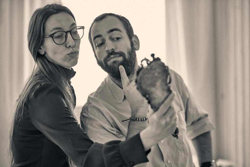 Two people posing playfully with a small mirror in sepia-toned photo, woman wearing glasses, man with beard making shush gesture - © Pascal Recchia. All rights reserved.