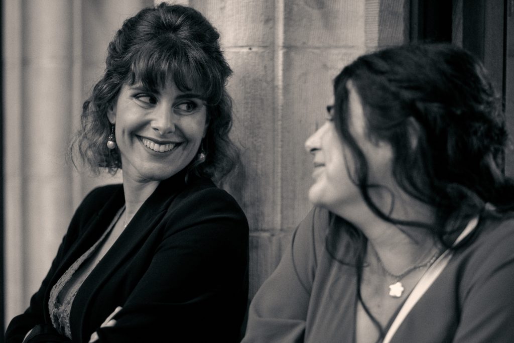 Two women in conversation, one in black blazer, other in profile wearing light top, vintage sepia tone - © Pascal Recchia. All rights reserved.