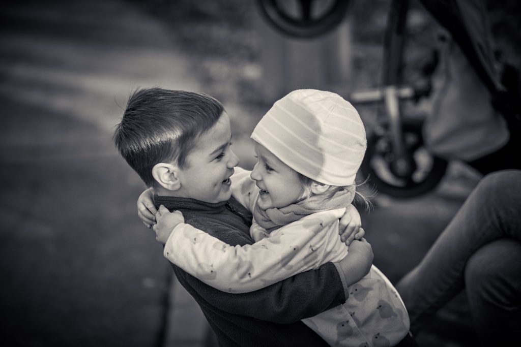 Two young children embracing in warm hug, black and white photograph showing sibling affection and childhood bond - © Pascal Recchia. All rights reserved.