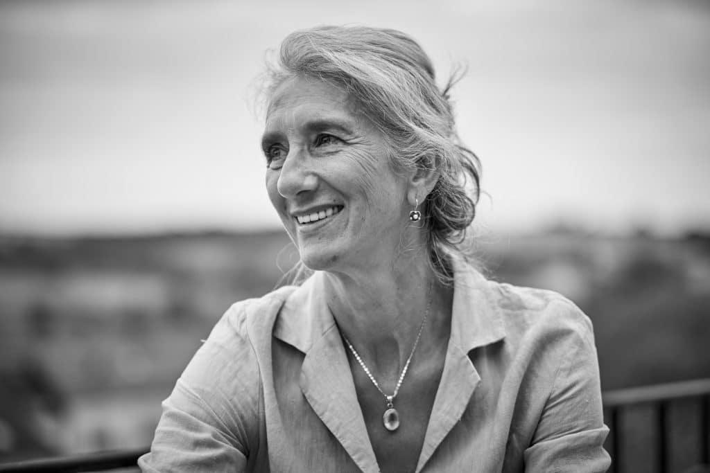 Black and white portrait of smiling middle-aged woman with wavy hair in casual blazer, shot with soft natural lighting - © Pascal Recchia. All rights reserved.