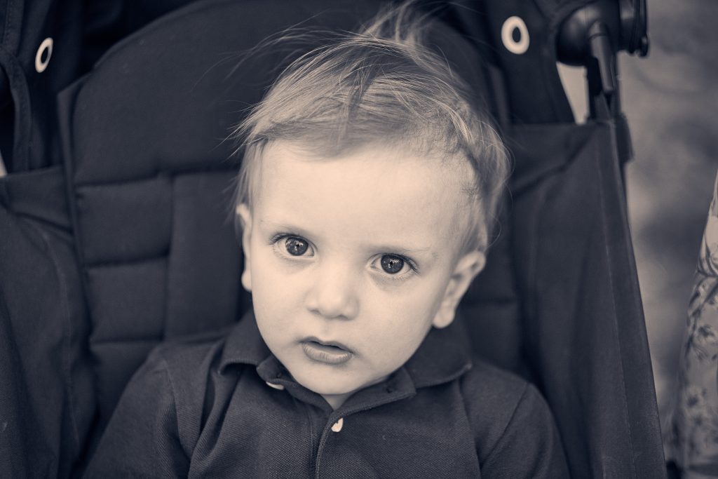 Black and white portrait of young child with blonde hair wearing dark jacket, looking directly at camera with serious expression - © Pascal Recchia. All rights reserved.