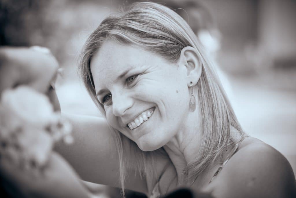Smiling woman with blonde hair and earrings in sepia-toned portrait photo with soft background blur - © Pascal Recchia. All rights reserved.