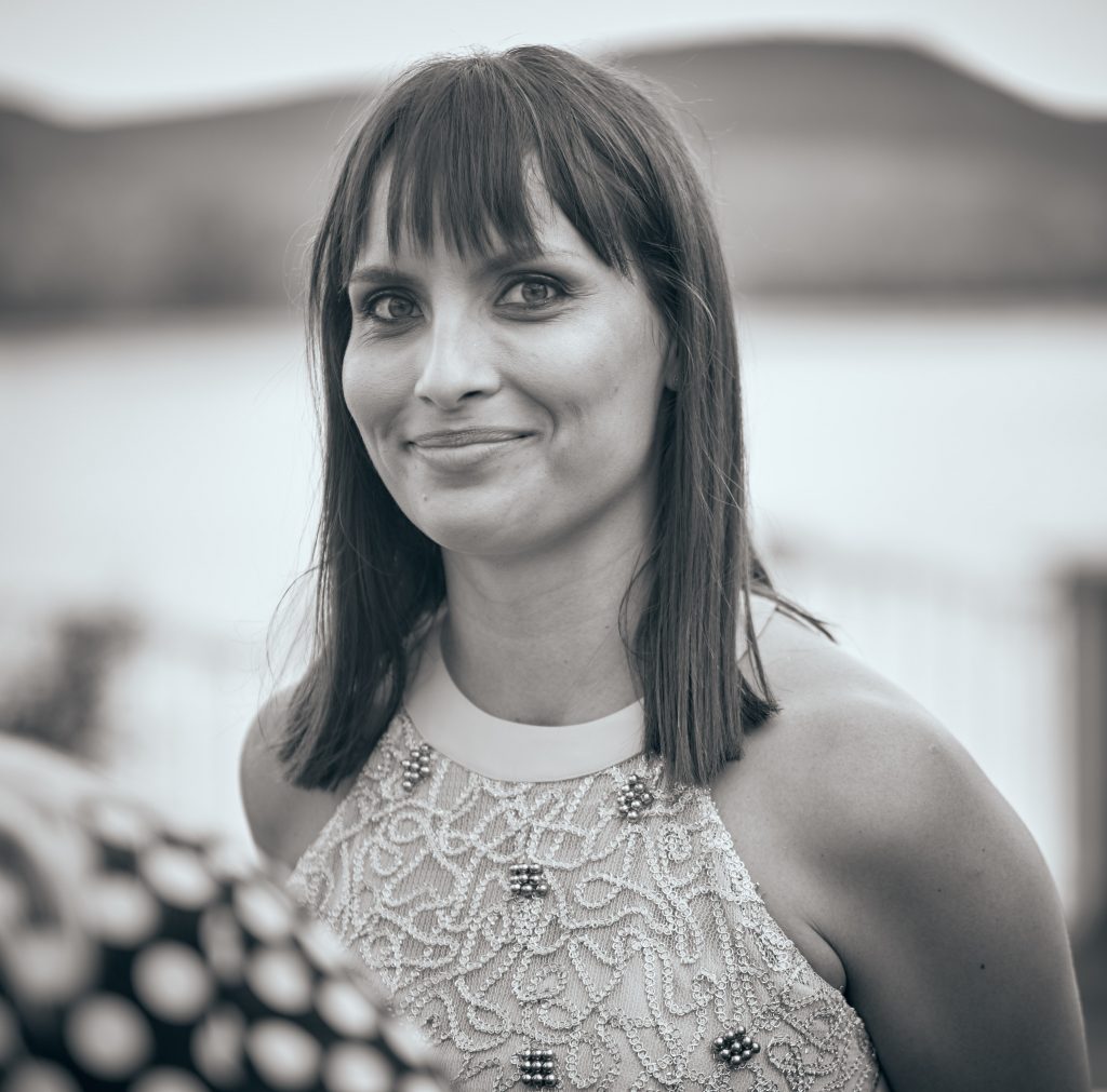 Professional black and white portrait of woman with bangs and shoulder-length hair wearing ornate lace sleeveless top
