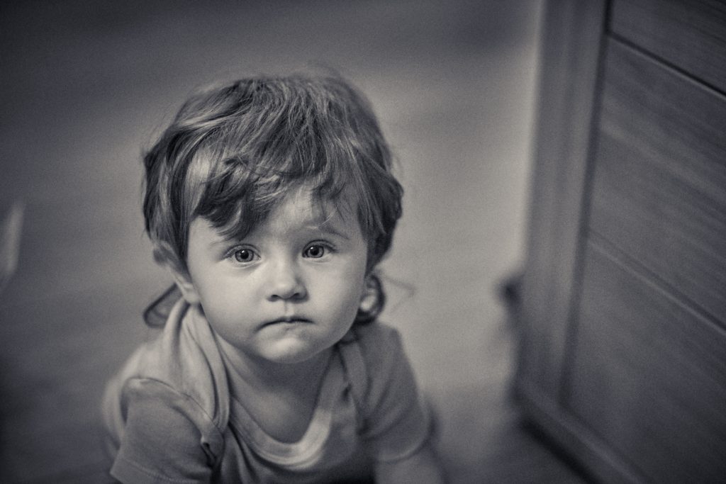 Black and white portrait of young child with tousled hair, looking directly at camera with serious expression - © Pascal Recchia. All rights reserved.