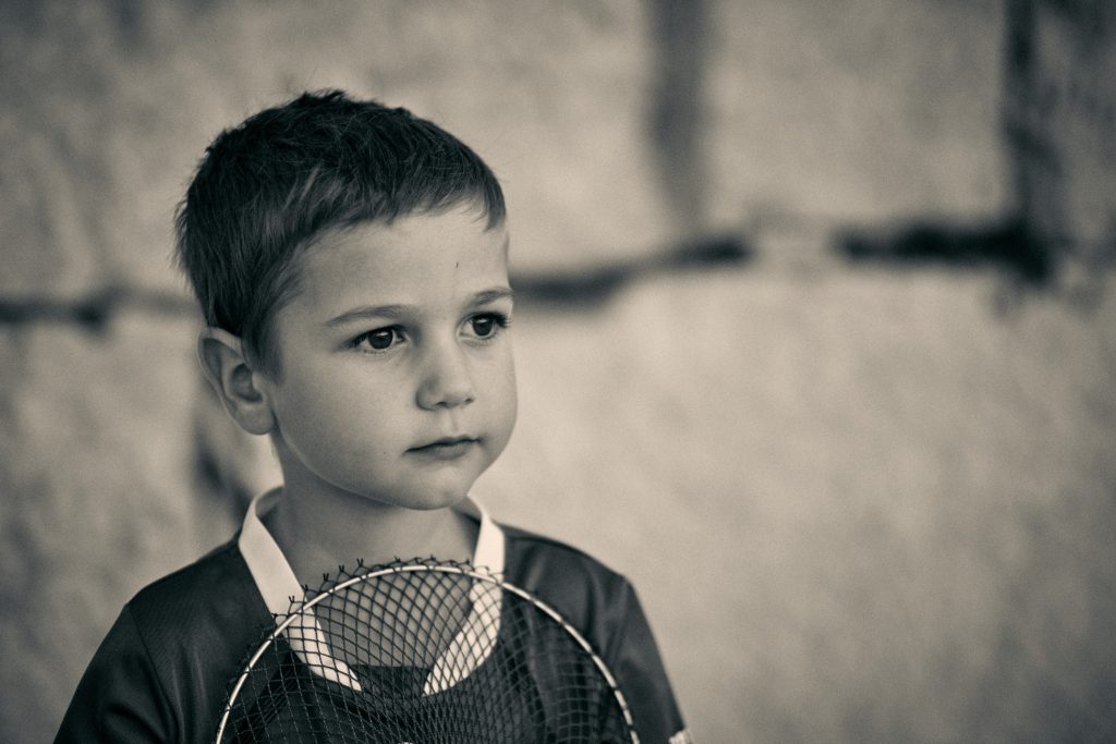 Young child holding landing net in black and white portrait photo with soft focus background in outdoor setting - © Pascal Recchia. All rights reserved.