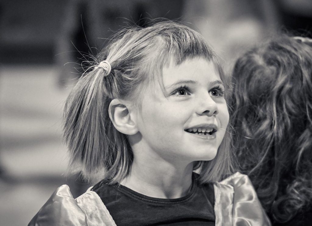 Smiling young girl with blonde ponytail in black and white portrait photo - © Pascal Recchia. All rights reserved.