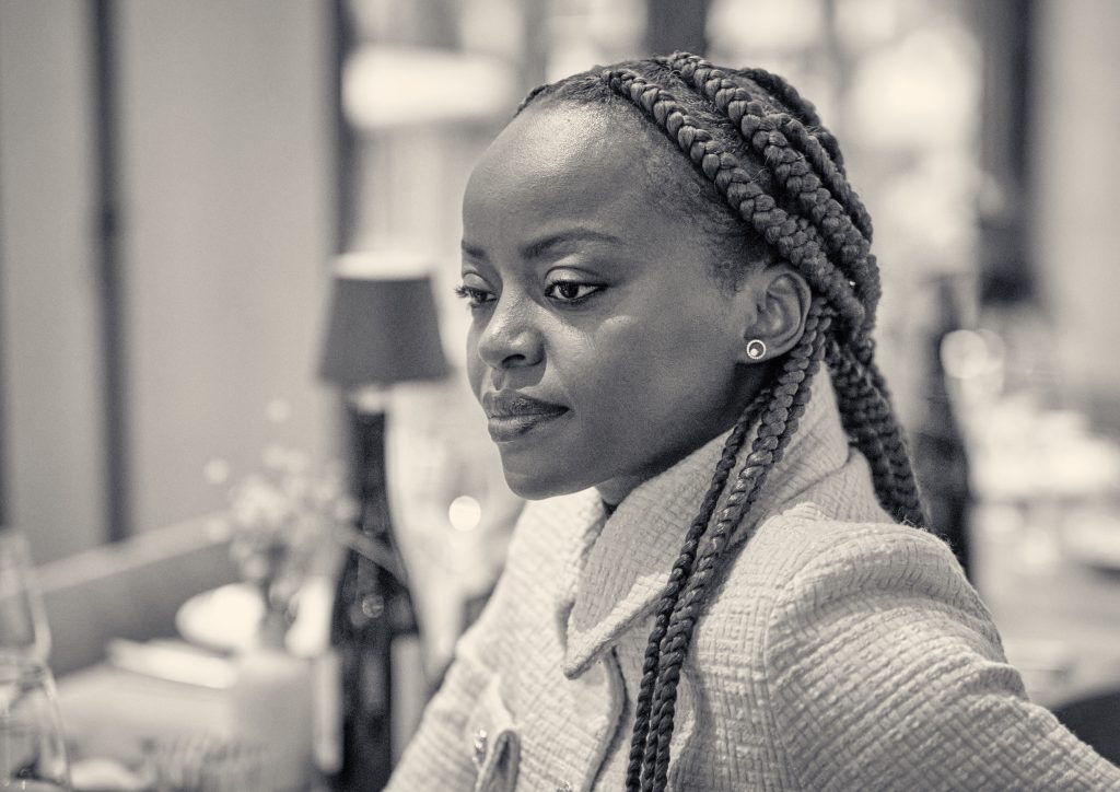 Portrait of young Black woman with braided hair wearing cream cardigan, looking thoughtfully to the side in sepia tone - © Pascal Recchia. All rights reserved.