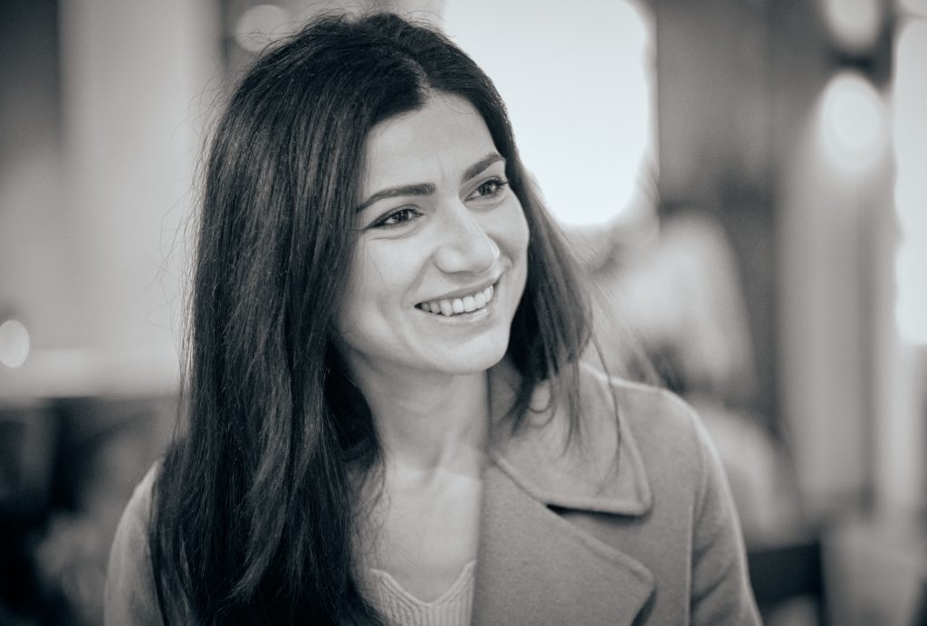 Woman with long dark hair smiling warmly in sepia-toned professional portrait photo with soft background lighting - © Pascal Recchia. All rights reserved.